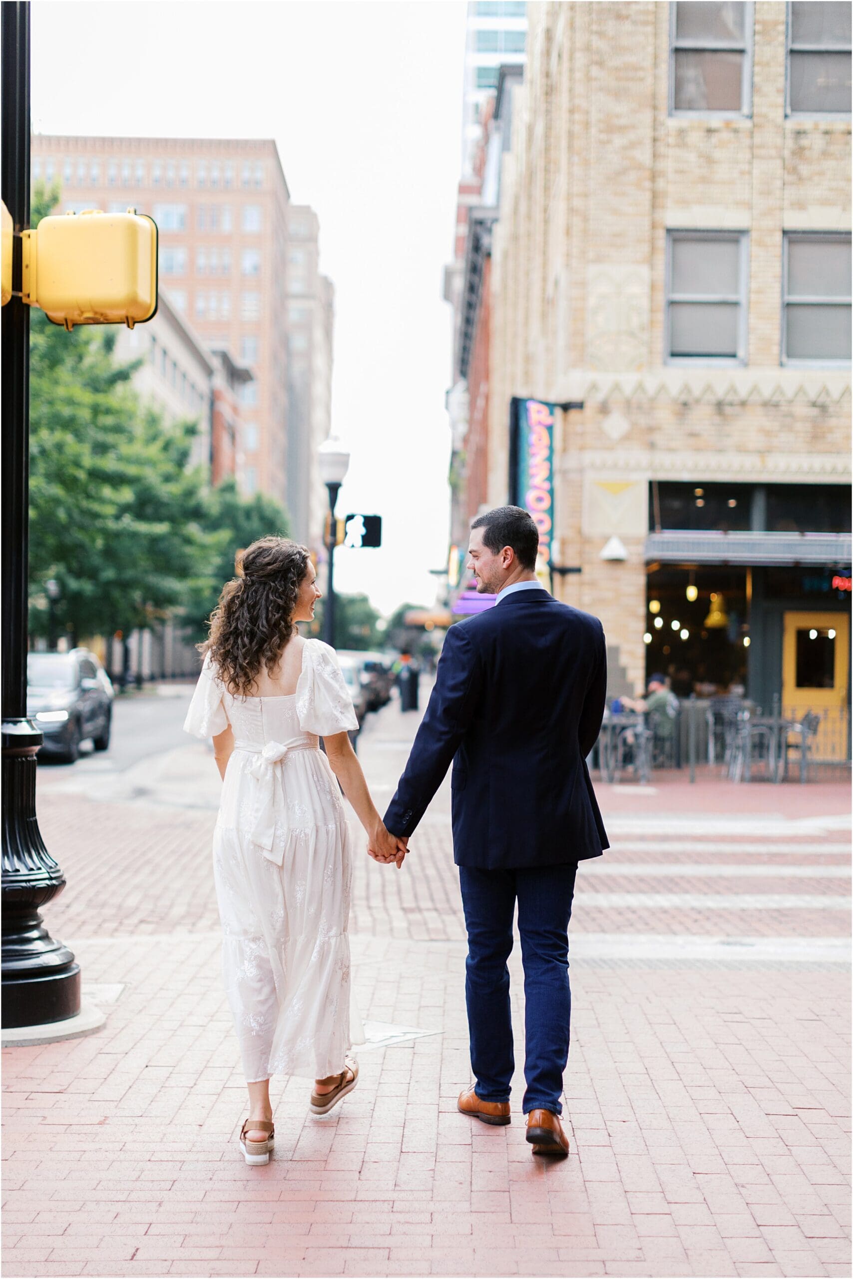 a couple holding hands walking away in down town fort worth