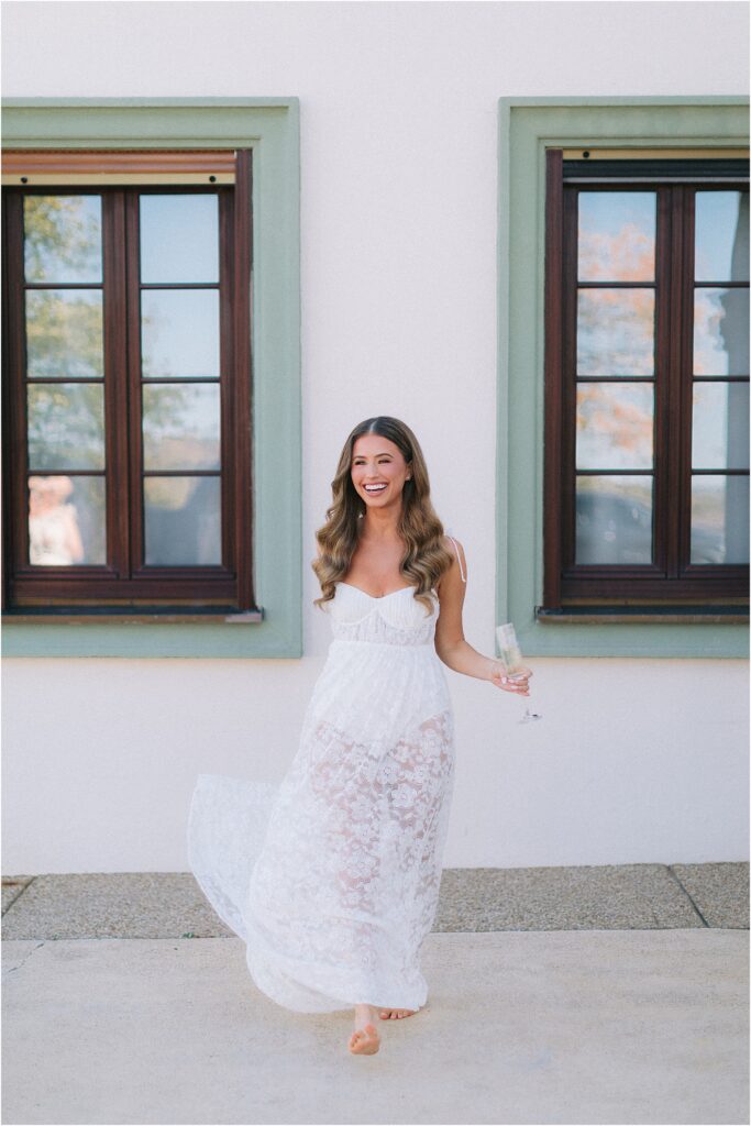 bride with lace nightgown holding monogrammed champagne glass