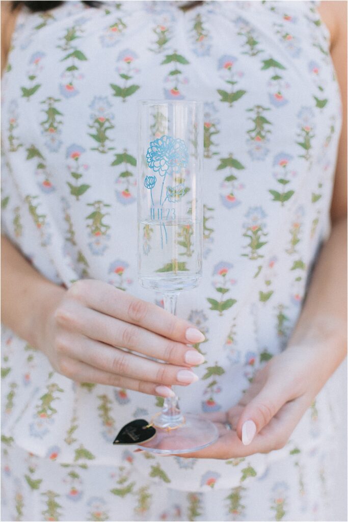 bridesmaid holding a monogrammed champagne glass with blue flower